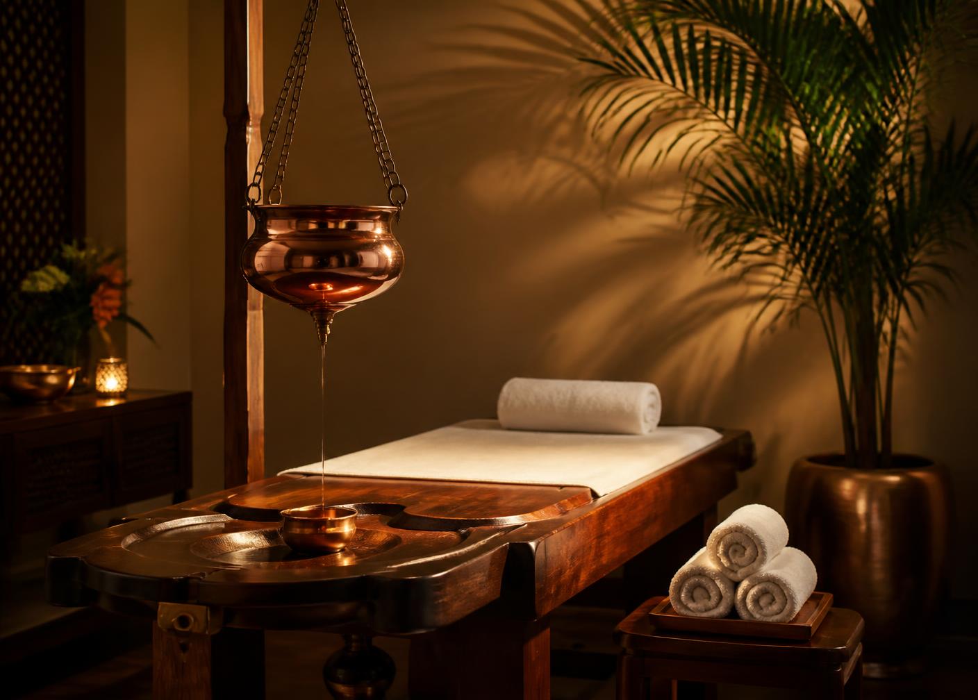 Warmly lit wellness therapy room prepared for an oil therapy session